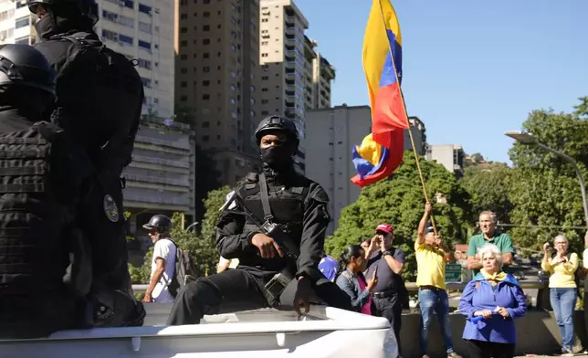 Security forces patrol past opponents of Venezuelan President Nicolas Maduro who are demonstrating the day before his inauguration for a third term in Caracas, Venezuela, Thursday, Jan. 9, 2025. (AP Photo/Ariana Cubillos)