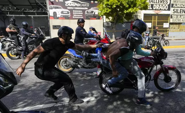 Police pursue opponents of Venezuelan President Nicolas Maduro, two people on the motorcycle at right, during a protest the day before Maduro's inauguration for a third term in Caracas, Venezuela, Thursday, Jan. 9, 2025. (AP Photo/Matias Delacroix)