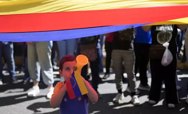 A youth plays a horn during a protest by opponents of Venezuelan President Nicolas Maduro the day before his inauguration for a third term in Caracas, Venezuela, Thursday, Jan. 9, 2025. (AP Photo/Matias Delacroix)