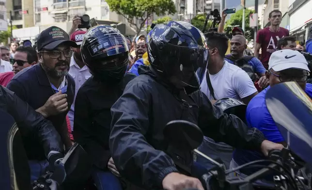 Opposition leader Maria Corina Machado, wearing a helmet at left, sits on the back of a motorcycle as she is driven away after addressing people at a protest against President Nicolas Maduro in Caracas, Venezuela, Thursday, Jan. 9, 2025, the day before his inauguration for a third term. (AP Photo/Matias Delacroix)