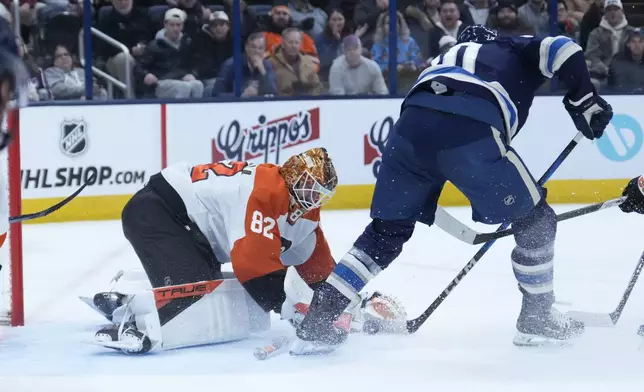 Philadelphia Flyers goaltender Ivan Fedotov (82) reaches to cover the puck next to Columbus Blue Jackets left wing Dmitri Voronkov (10) in the second period of an NHL hockey game Tuesday, Jan. 14, 2025, in Columbus, Ohio. (AP Photo/Sue Ogrocki)
