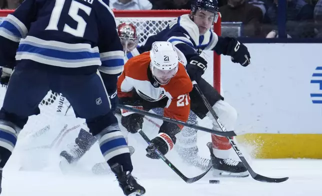 Philadelphia Flyers center Scott Laughton (21) reaches for the puck in front of Columbus Blue Jackets goaltender Daniil Tarasov, left, and defenseman Denton Mateychuk, right, in the second period of an NHL hockey game Tuesday, Jan. 14, 2025, in Columbus, Ohio. (AP Photo/Sue Ogrocki)