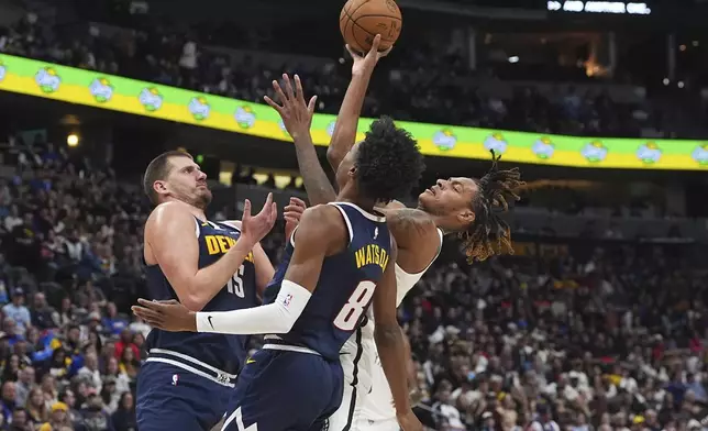 Brooklyn Nets forward Noah Clowney, right, drives to the basket as Denver Nuggets center Nikola Jokic, left, and forward Peyton Watson (8) defend in the first half of an NBA basketball game Friday, Jan. 10, 2025, in Denver. (AP Photo/David Zalubowski)