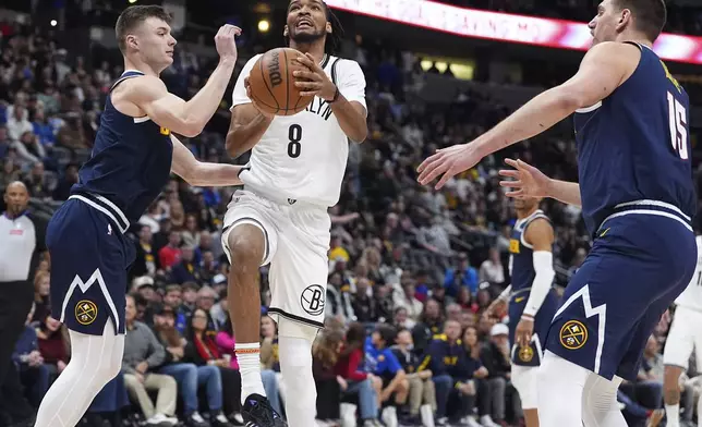Brooklyn Nets guard De'Anthony Melton (8) drives the lane between Denver Nuggets guard Christian Braun, left, and center Nikola Jokic, right, in the first half of an NBA basketball game Friday, Jan. 10, 2025, in Denver. (AP Photo/David Zalubowski)