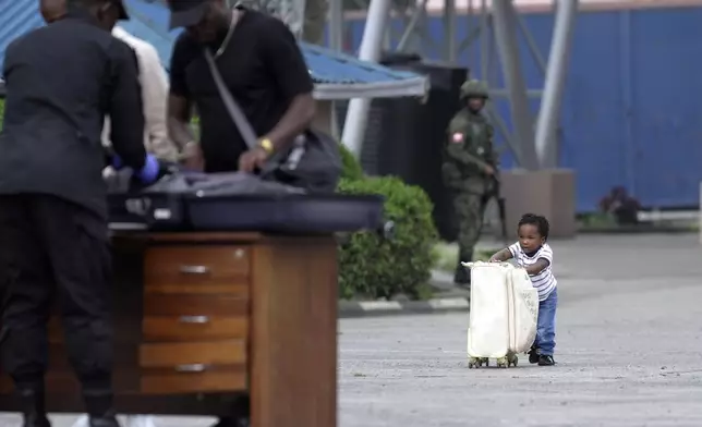 A child pushes a suitcase towards Rwanda security officials checking people crossing from Congo in Gisenyi, Rwanda, Wednesday, Jan. 29, 2025, following M23 rebels' advances into eastern Congo's capital Goma. (AP Photo/Brian Inganga)