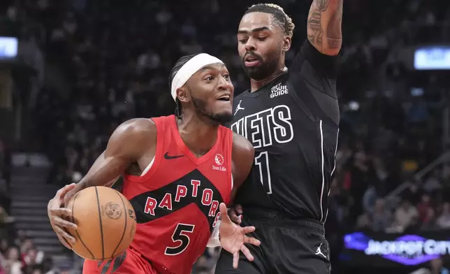 Toronto Raptors' Immanuel Quickley (5) drives at Brooklyn Nets' D'Angelo Russell (1) during the first half of an NBA basketball game in Toronto on Wednesday, Jan. 1, 2025. (Chris Young/The Canadian Press via AP)