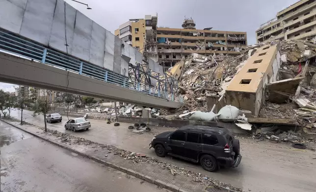 FILE - Cars pass under a collapsed pedestrian bridge and next to destroyed building that were hit in an Israeli airstrike in Dahiyeh, in the southern suburb of Beirut, Lebanon, Nov. 19, 2024. (AP Photo/Hussein Malla, File)