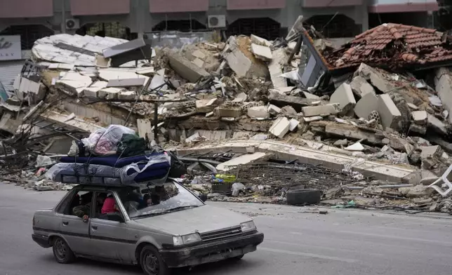 FILE - Displaced residents drive past the rubble of destroyed buildings as they return to their villages, following a ceasefire between Israel and Hezbollah that went into the day before, in Tyre, southern Lebanon, Nov. 27, 2024. (AP Photo/Hussein Malla, File)