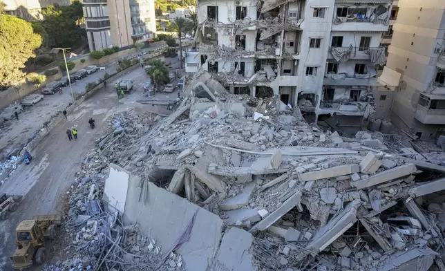 FILE - Rescue workers use a bulldozer to remove rubble of destroyed buildings at the site of an Israeli airstrike that hit several branches of the Hezbollah-run Qard al-Hassan Association in Beirut's southern suburb, Lebanon, Oct. 21, 2024. (AP Photo/Hassan Ammar, File)