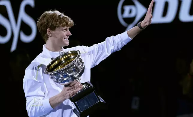 Jannik Sinner of Italy waves as he carries the Norman Brookes Challenge Cup after defeating Alexander Zverev of Germany in the men's singles final at the Australian Open tennis championship in Melbourne, Australia, Sunday, Jan. 26, 2025. (AP Photo/Ng Han Guan)