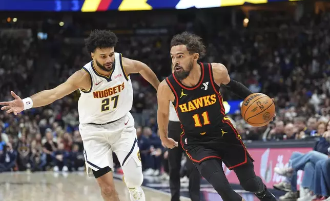 Atlanta Hawks guard Trae Young, right, drives to the basket past Denver Nuggets guard Jamal Murray in the first half of an NBA basketball game Wednesday, Jan. 1, 2025, in Denver. (AP Photo/David Zalubowski)