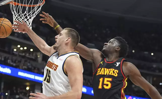 Denver Nuggets center Nikola Jokic, left, battles for control of the ball with Atlanta Hawks center Clint Capela in the first half of an NBA basketball game Wednesday, Jan. 1, 2025, in Denver. (AP Photo/David Zalubowski)