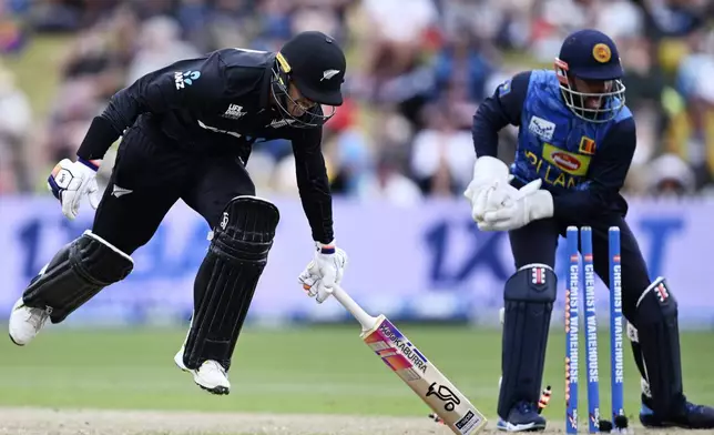 New Zealand's Mark Chapman, left, makes his ground as Sri Lanka wicketkeeper Kusal Mendis takes the bails off during their one day international cricket match in Hamilton, New Zealand. Wednesday, Jan. 8, 2025. (Andrew Cornaga/Photosport via AP)