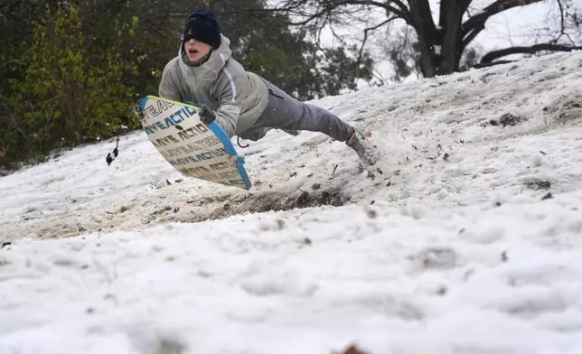 Luke Choat slides on a small snow covered hill Thursday, Jan. 9, 2025, in Richardson, Texas. (AP Photo/LM Otero)