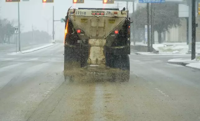 A truck treats a road for better driving conditions as snow falls Thursday, Jan. 9, 2025, in Dallas. (AP Photo/LM Otero)