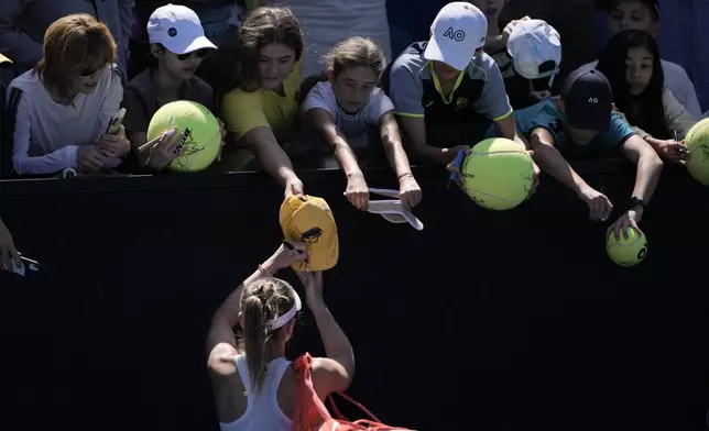 Paula Badosa of Spain signs autographs after defeating Marta Kostyuk of Ukraine in their third round match at the Australian Open tennis championship in Melbourne, Australia, Friday, Jan. 17, 2025. (AP Photo/Ng Han Guan)