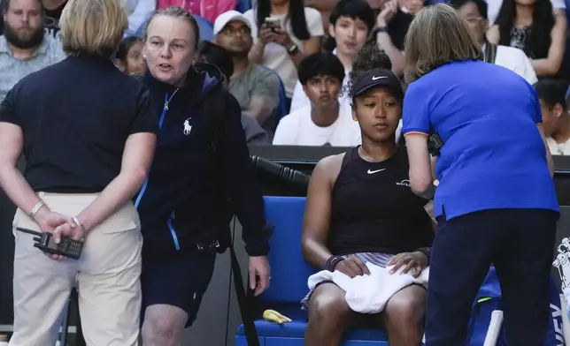 Naomi Osaka of Japan receives treatment from a trainer during her third round match against Belinda Bencic of Switzerland at the Australian Open tennis championship in Melbourne, Australia, Friday, Jan. 17, 2025. (AP Photo/Manish Swarup)