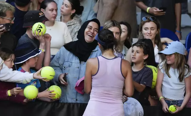 Belinda Bencic of Switzerland signs autographs following her third round match against Naomi Osaka of Japan at the Australian Open tennis championship in Melbourne, Australia, Friday, Jan. 17, 2025. (AP Photo/Manish Swarup)