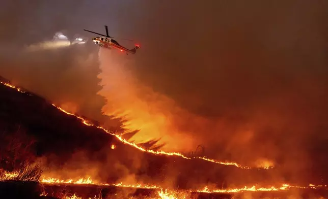 Water is dropped by helicopter on the Kenneth Fire in the West Hills section of Los Angeles, Thursday, Jan. 9, 2025. (AP Photo/Ethan Swope)