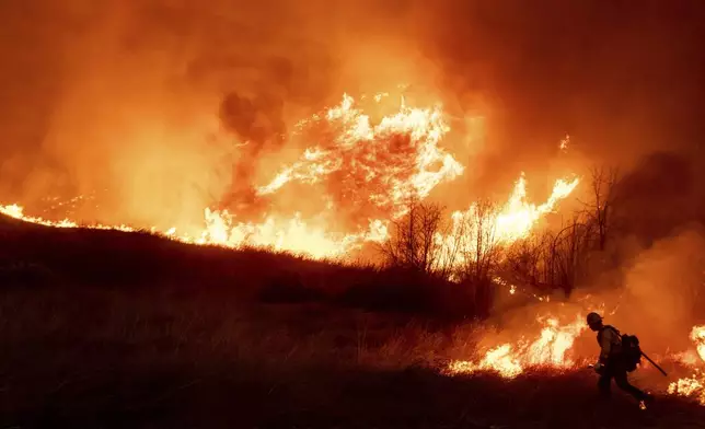 A firefighter sets a backburn in front of the advancing Kenneth Fire in the West Hills section of Los Angeles, Thursday, Jan. 9, 2025. (AP Photo/Ethan Swope)