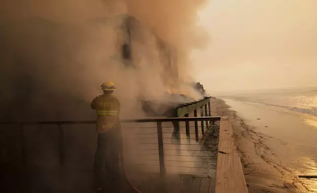 A firefighter protects a beach front property while fighting the Palisades Fire Thursday, Jan. 9, 2025 in Malibu, Calif. (AP Photo/Jae C. Hong)