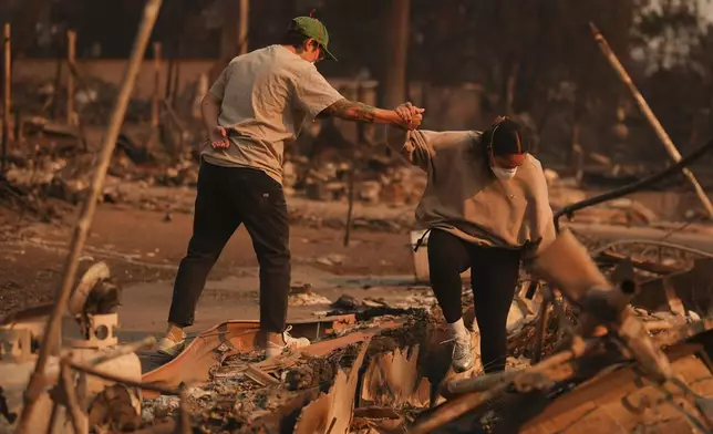 Two people hold hands while sifting through a fire-ravage property in the aftermath of the Eaton Fire Thursday, Jan. 9, 2025 in Altadena, Calif. (AP Photo/Eric Thayer)