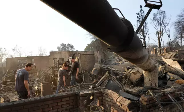 From left, Rob Ramsey, Christina Larson and Larson's husband Chris, the co-owner of the Rancho Bar, look through the ruins of the Rancho Bar a day after it was destroyed by the Eaton Fire, Thursday, Jan. 9, 2025, in Altadena, Calif. (AP Photo/Chris Pizzello)