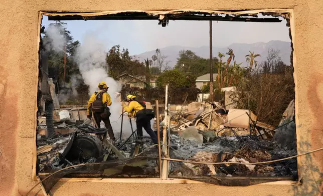 Firefighters extinguish burning embers at a house on Santa Rosa Avenue, also known as Christmas Tree Lane, Thursday, Jan. 9, 2025, in Altadena, Calif. (AP Photo/Chris Pizzello)