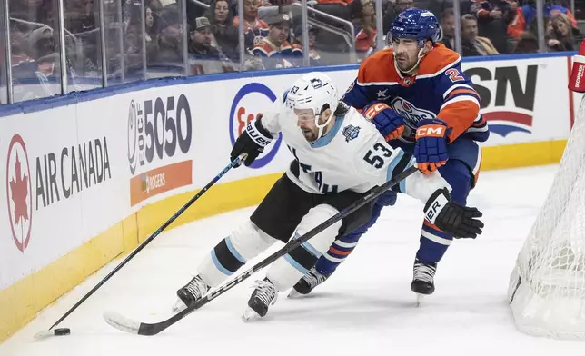 Utah Hockey Club's Michael Carcone (53) and Edmonton Oilers' Evan Bouchard (2) battle for the puck during the third period of an NHL hockey game in Edmonton, Alberta on Tuesday, Dec. 31, 2024. (Jason Franson/The Canadian Press via AP)