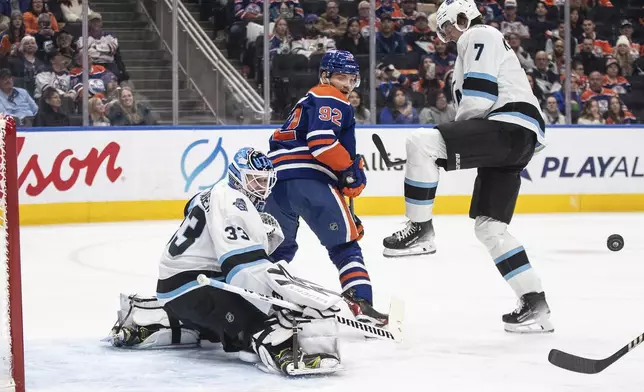 Utah Hockey Club goalie Jaxson Stauber (33) makes the save as Edmonton Oilers' Vasily Podkolzin (92) and Michael Kesselring (7) battle in front during the second period of an NHL hockey game in Edmonton, Alberta on Tuesday, Dec. 31, 2024. (Jason Franson/The Canadian Press via AP)