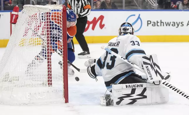 Utah Hockey Club goalie Jaxson Stauber (33) is scored against by Edmonton Oilers' Ryan Nugent-Hopkins (93) during the second period of an NHL hockey game in Edmonton, Alberta on Tuesday, Dec. 31, 2024. (Jason Franson/The Canadian Press via AP)