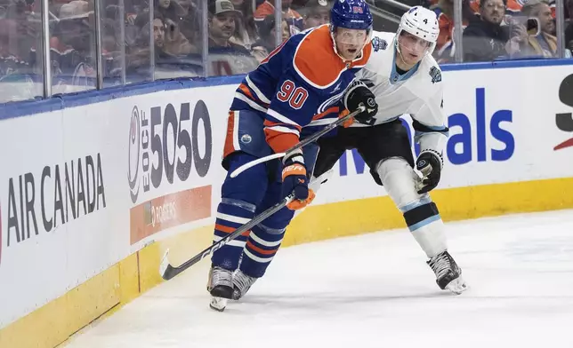 Utah Hockey Club's Juuso Valimaki (4) and Edmonton Oilers' Corey Perry (90) battle for the puck during the second period of an NHL hockey game in Edmonton, Alberta on Tuesday, Dec. 31, 2024. (Jason Franson/The Canadian Press via AP)