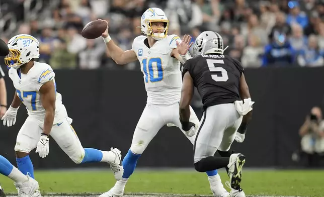 Los Angeles Chargers quarterback Justin Herbert (10) passes as Las Vegas Raiders linebacker Divine Deablo (5) applies pressure during the first half of an NFL football game in Las Vegas, Sunday, Jan. 5, 2025. (AP Photo/Abbie Parr)