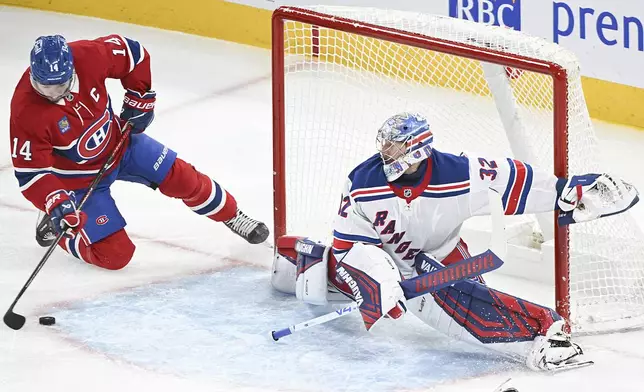 Montreal Canadiens' Nick Suzuki (14) moves in against New York Rangers goaltender Jonathan Quick (32) during second-period NHL hockey game action in Montreal, Sunday, Jan. 19, 2025. (Graham Hughes/The Canadian Press via AP)