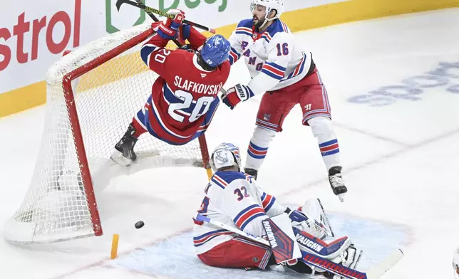 Montreal Canadiens' Juraj Slafkovsky (20) scores against New York Rangers goaltender Jonathan Quick (32) as Rangers' Vincent Trocheck (16) defends during third-period NHL hockey game action in Montreal, Sunday, Jan. 19, 2025. (Graham Hughes/The Canadian Press via AP)