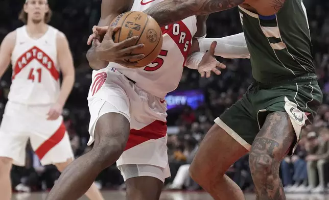 Toronto Raptors guard Immanuel Quickley, center, and Milwaukee Bucks guard Gary Trent Jr., right, vie for control of the ball during the first half of an NBA basketball game in Toronto, Monday, Jan. 6, 2025. (Nathan Denette/The Canadian Press via AP)