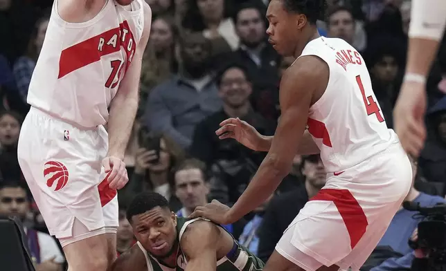 Milwaukee Bucks forward Giannis Antetokounmpo gets squeezed between Toronto Raptors center Jakob Poeltl and teammate Scottie Barnes (4) during the first half of an NBA basketball game in Toronto, Monday, Jan. 6, 2025. (Nathan Denette/The Canadian Press via AP)