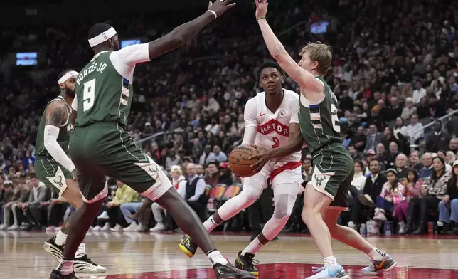 Toronto Raptors guard RJ Barrett (9) drives between Milwaukee Bucks forward Bobby Portis (9) and teammate AJ Green during the first half of an NBA basketball game in Toronto, Monday, Jan. 6, 2025. (Nathan Denette/The Canadian Press via AP)