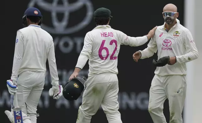 Australia's Nathan Lyon, right, is congratulated by Travis Head after taking the wicket of India's Shubman Gill, left, during play on the first day of the fifth cricket test between India and Australia at the Sydney Cricket Ground, in Sydney, Australia, Friday, Jan. 3, 2025. (AP Photo/Mark Baker)