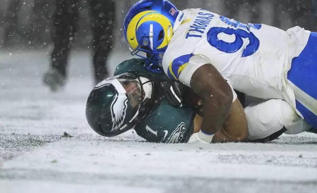 Philadelphia Eagles quarterback Jalen Hurts (1) is tackled by Los Angeles Rams linebacker Keir Thomas (96) during the second half of an NFL football NFC divisional playoff game Sunday, Jan. 19, 2025, in Philadelphia. (AP Photo/Derik Hamilton)