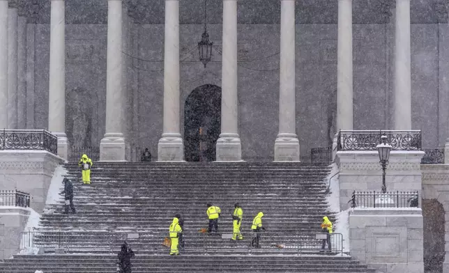 Workers clear steps at the Capitol as snow falls ahead of a joint session of Congress to certify the votes from the Electoral College in the presidential election, in Washington, Monday, Jan. 6, 2025. (AP Photo/J. Scott Applewhite)