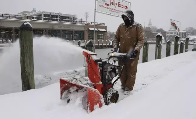 Tony Savage, who works for the city of Annapolis, clears snow along the City Dock in Annapolis, Md., Monday, Jan. 6, 2025. (AP Photo/Brian Witte)