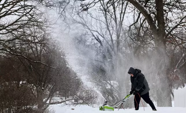 Dave Thomasson uses an electric snowblower to clear his driveway in the Webster Oaks subdivision of Webster Groves, Mo. as residents started clearing a path on Monday, Jan. 6, 2025. (Robert Cohen/St. Louis Post-Dispatch via AP)