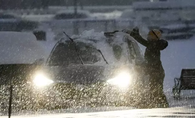 A person clears off a car during a winter snow storm in Washington, Monday, Jan. 6, 2025. (AP Photo/Matt Rourke)