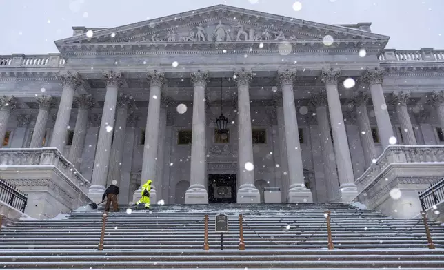 Workers clear steps at the Capitol as snow falls ahead of a joint session of Congress to certify the votes from the Electoral College in the presidential election, in Washington, Monday, Jan. 6, 2025. (AP Photo/J. Scott Applewhite)