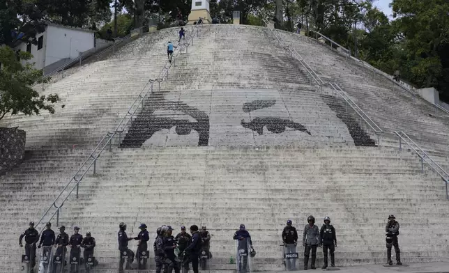 Bolivarian National Police stand guard in front of steps featuring a giant portrait of the eyes of the late President Hugo Chavez ahead of President Nicolas Maduro's swearing-in for a third term, in Caracas, Venezuela, Sunday, Jan. 5, 2025. (AP Photo/Matias Delacroix)