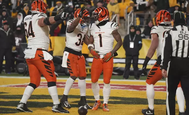 Cincinnati Bengals wide receiver Ja'Marr Chase (1) celebrates scoring a touchdown with center Ted Karras (64) and running back Khalil Herbert (34) during the first half of an NFL football game against the Pittsburgh Steelers in Pittsburgh, Saturday, Jan. 4, 2025. (AP Photo/Gene J. Puskar)