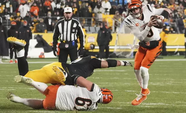 Cincinnati Bengals quarterback Joe Burrow (9) avoids Pittsburgh Steelers defensive tackle Cameron Heyward (97) with Cincinnati Bengals guard Cordell Volson (67) during the second half of an NFL football game in Pittsburgh, Saturday, Jan. 4, 2025. (AP Photo/Gene J. Puskar)