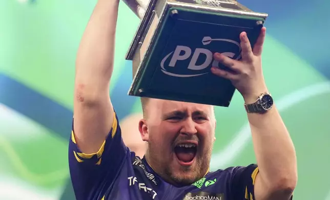 Luke Littler of England holds the trophy after winning the final against Michael van Gerwen of the Netherlands at the World Darts Championship at Alexandra Palace in London, Friday, Jan. 3, 2025. (AP Photo/Kirsty Wigglesworth)