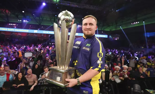 Luke Littler of England holds the trophy after winning the final against Michael van Gerwen of the Netherlands at the World Darts Championship at Alexandra Palace in London, Friday, Jan. 3, 2025. (AP Photo/Kirsty Wigglesworth)